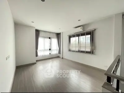 Spacious empty room with large windows and modern flooring, perfect for customization.