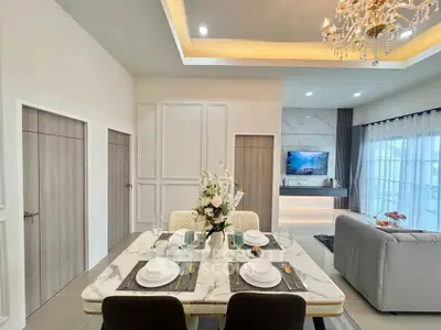 Elegant open-plan living and dining area with modern decor and chandelier lighting.