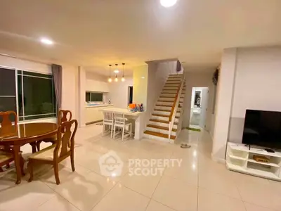 Spacious open-plan living area with elegant dining set and modern kitchen, featuring a stylish staircase.