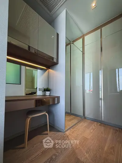 Modern study area with sleek wooden desk and stool, adjacent to mirrored closet doors.