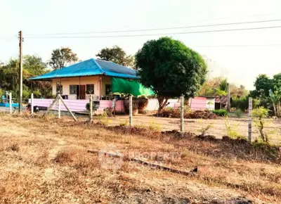 Charming countryside house with blue roof and spacious yard, perfect for serene living.