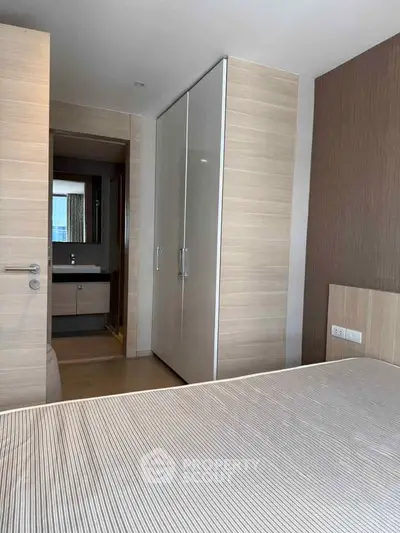 Modern bedroom with sleek wardrobe and ensuite bathroom in stylish apartment.