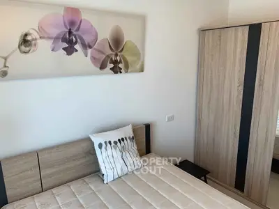 Modern bedroom with stylish wooden wardrobe and floral wall art