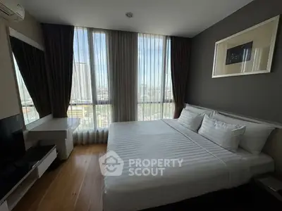 Modern bedroom with large windows and city view, featuring elegant decor and natural light.