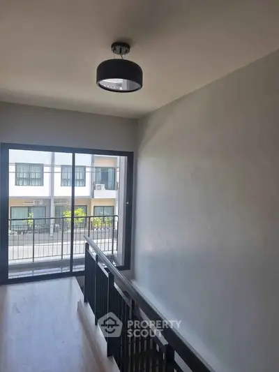 Modern townhouse interior with sleek staircase and large window offering natural light and street view.