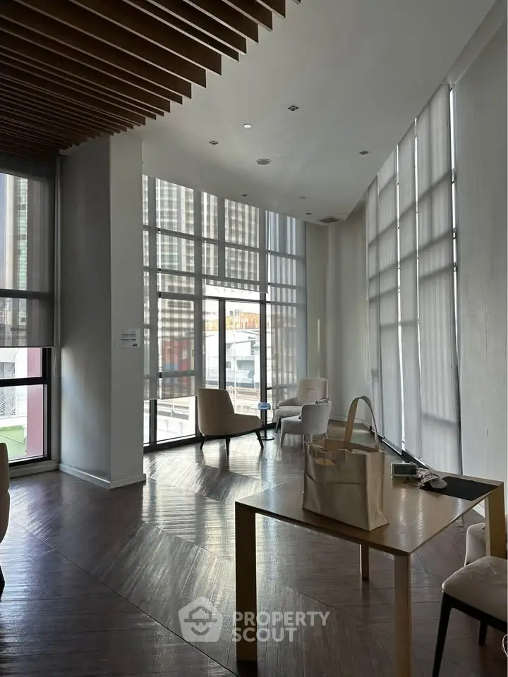 Modern living room with high ceilings and large windows offering city views.