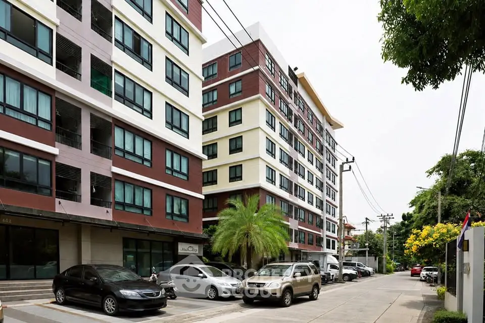 Modern apartment buildings with street view and parked cars, showcasing urban living.