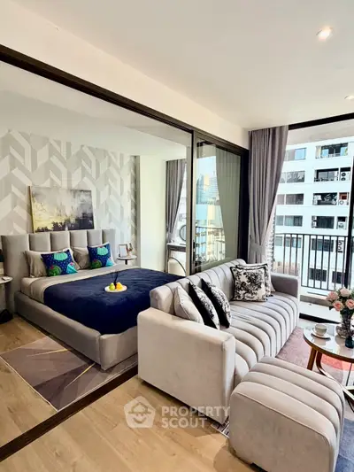 Modern open-plan living room and bedroom with stylish decor and city view balcony.