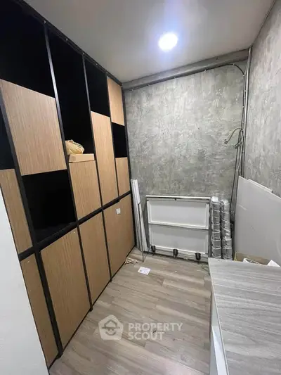 Modern storage room with sleek wooden cabinets and concrete walls, perfect for organized living.