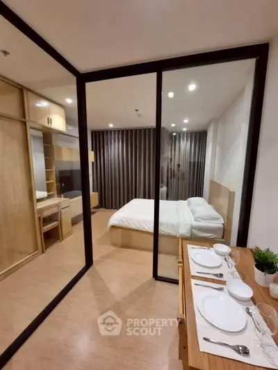 Modern bedroom with glass partition and dining area, featuring sleek wooden furniture and cozy ambiance.