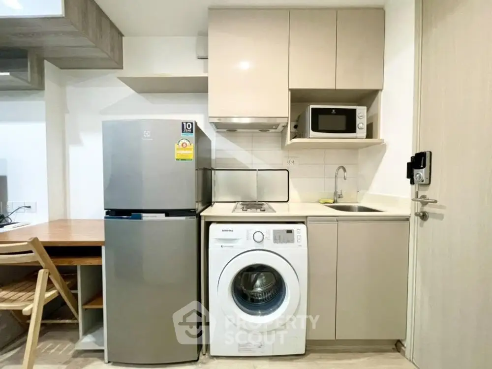 Compact kitchen with modern appliances including fridge, washing machine, and microwave.