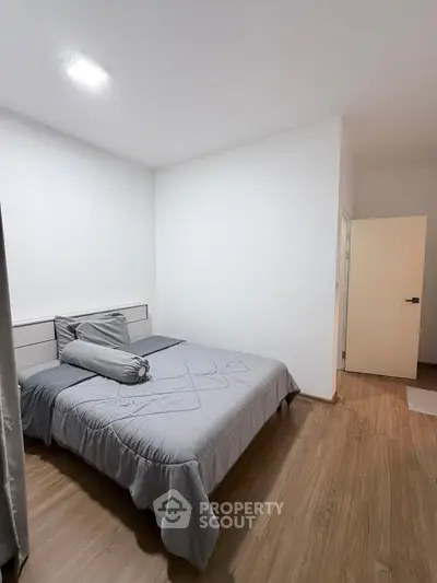 Modern minimalist bedroom with wooden flooring and cozy bedding