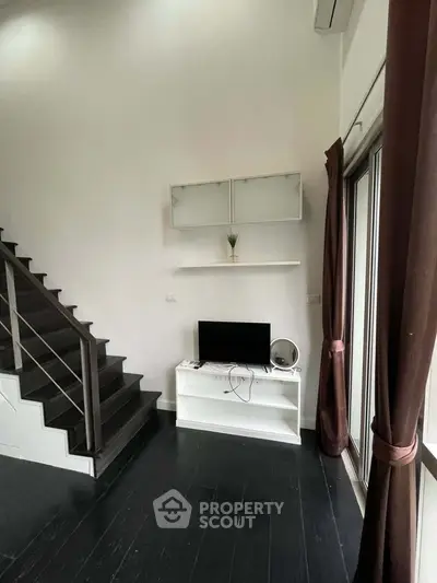 Modern interior with sleek staircase and minimalist TV setup in stylish living space.