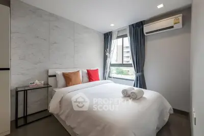 Modern bedroom with cozy bed, stylish decor, and natural light from large window.