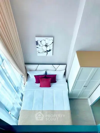 Modern bedroom with stylish decor and large window offering natural light.