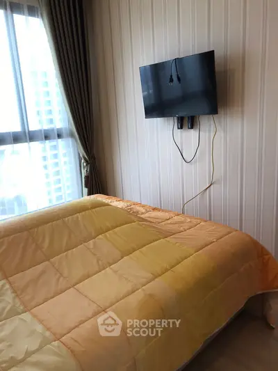 Cozy bedroom with wall-mounted TV and large window with curtains