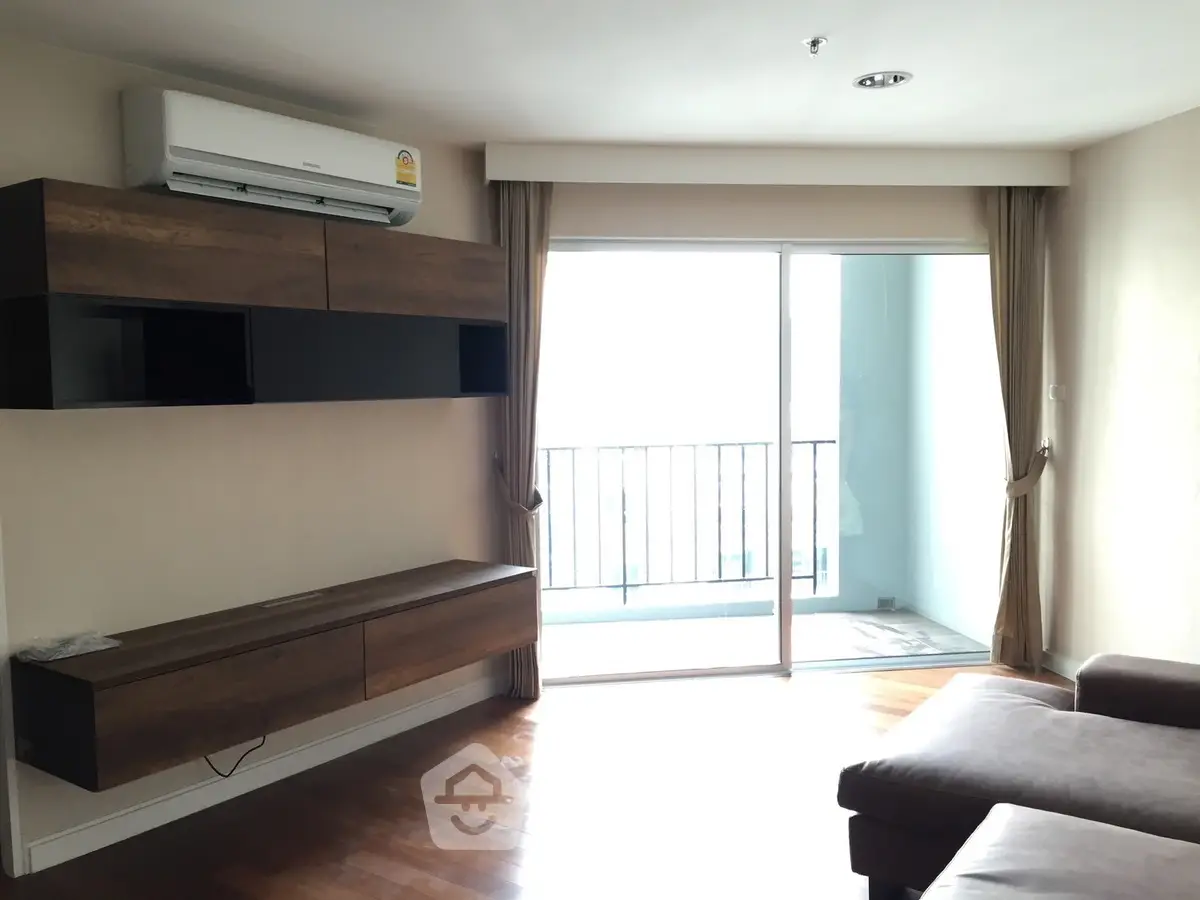 Modern living room with balcony access and stylish wooden cabinetry.