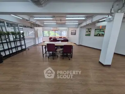 Spacious open-plan office with modern decor and large windows for natural light.