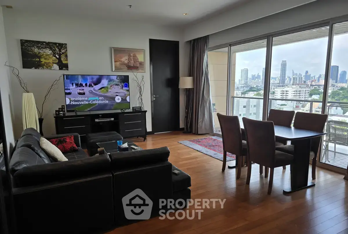 Spacious living room with city view, modern furniture, and wooden flooring in a high-rise apartment.