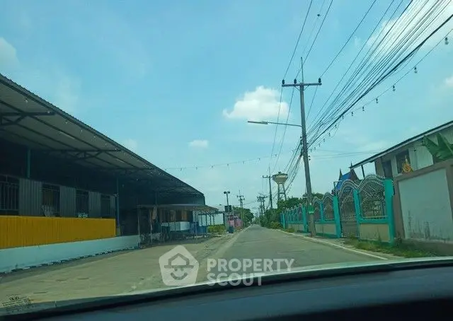 Street view with industrial buildings and clear sky, potential real estate development area.