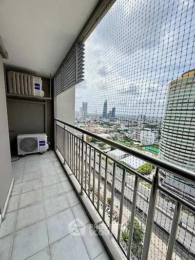 Spacious balcony with city view and safety netting in modern high-rise apartment.