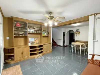 Spacious living room with wooden cabinetry and dining area, ideal for family gatherings.