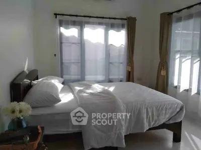 Cozy bedroom with natural light and elegant curtains, perfect for relaxation and comfort.