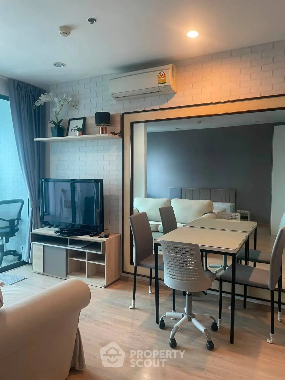 Modern living room with dining area, featuring stylish furniture and a large mirror enhancing space.