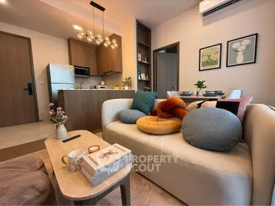 Modern living room with stylish decor and open kitchen layout, featuring cozy seating and elegant lighting.