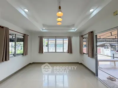 Spacious empty room with large windows and modern lighting, perfect for customization.