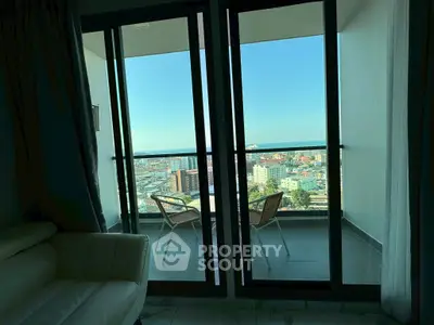 Stunning balcony view with cozy seating overlooking cityscape and ocean horizon.