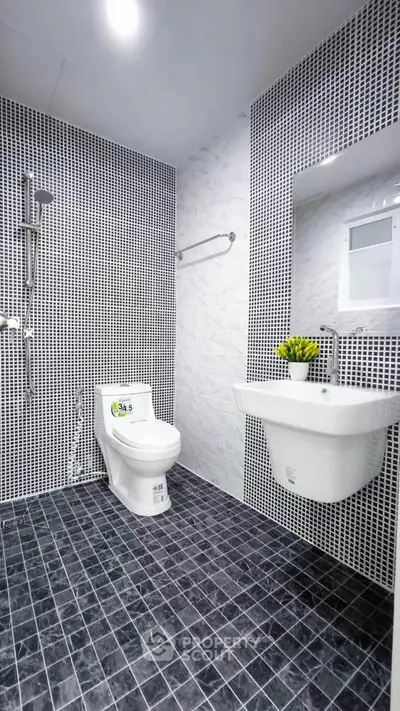 Modern bathroom with stylish black and white tile design and sleek fixtures.