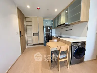 Modern kitchen with sleek cabinets, built-in appliances, and compact dining area in a stylish apartment.
