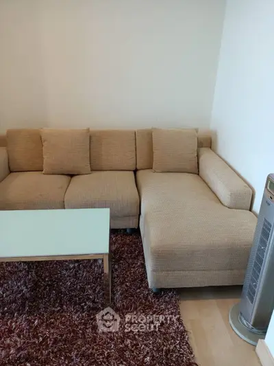Cozy living room with beige sectional sofa and modern glass coffee table on plush rug.