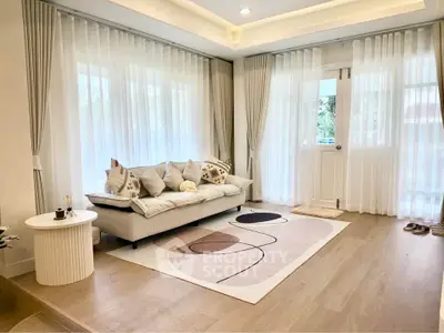 Elegant living room with modern decor, featuring a cozy sofa, stylish rug, and large windows with sheer curtains.