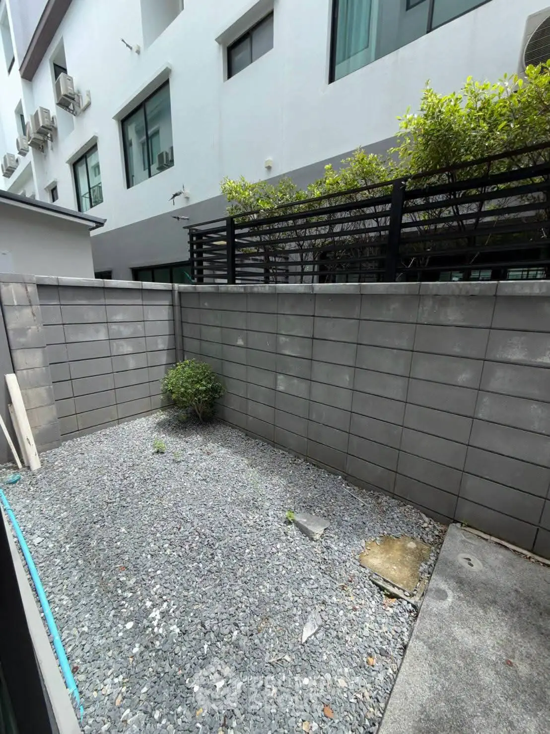 Modern townhouse exterior with private gravel yard and greenery, ideal for urban living.