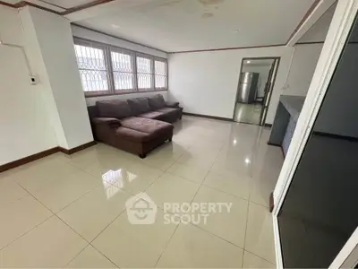 Spacious living room with modern sofa and large windows in a bright apartment.