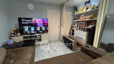 Cozy living room with modern decor and entertainment setup, featuring a large TV and comfortable seating.