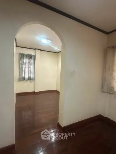 Charming interior with elegant archway and polished wooden floors, perfect for cozy living.