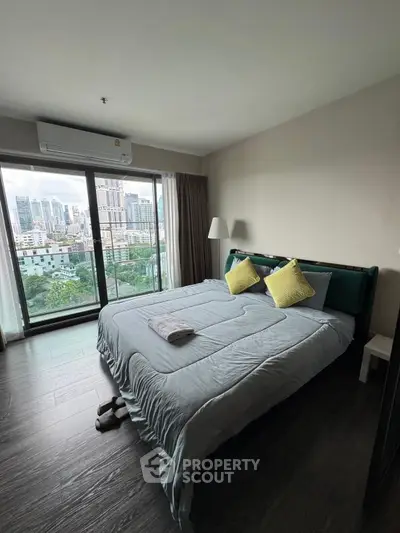 Spacious bedroom with city view and modern decor in high-rise apartment.