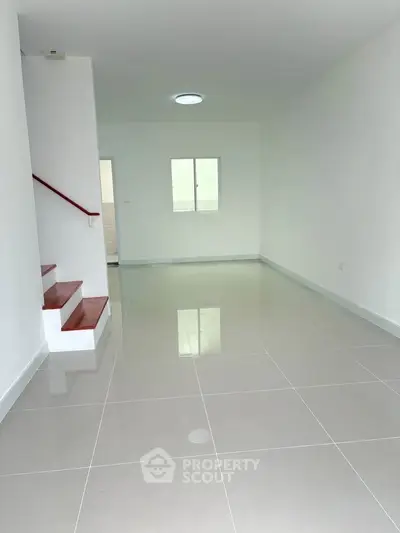 Spacious minimalist living room with glossy tiled floors and staircase
