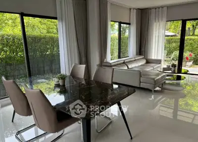 Modern living room with sleek furniture and large windows overlooking lush greenery.