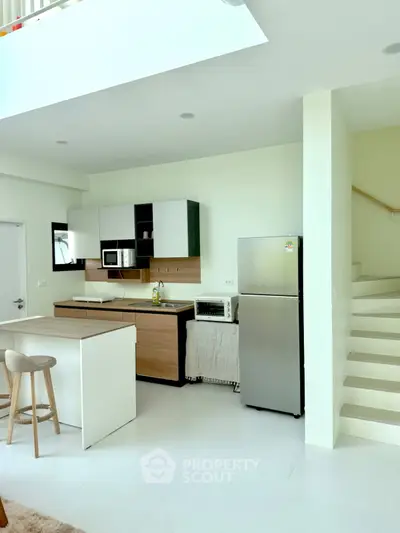 Modern kitchen with sleek design, featuring stainless steel fridge and minimalist cabinetry in open layout.