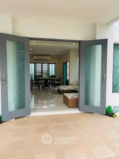 Spacious living room with elegant decor and large glass doors opening to a bright balcony.