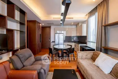 Modern living room with open kitchen, stylish furniture, and natural light.