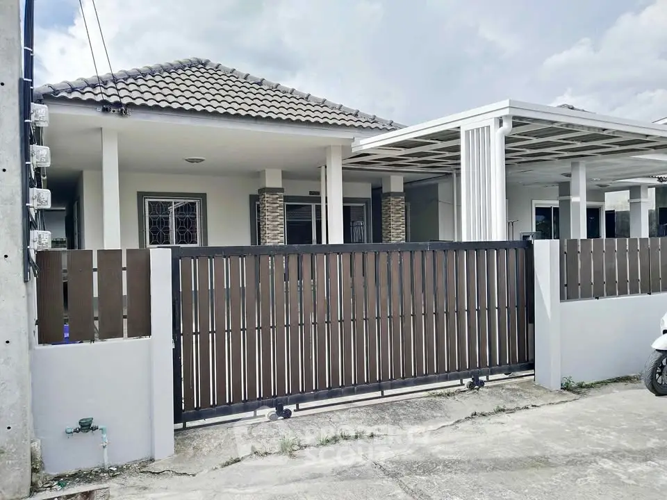 Charming single-story house with modern facade and gated entrance in a serene neighborhood.