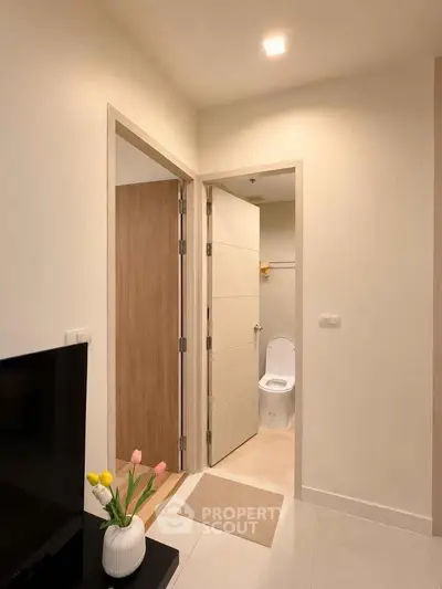 Modern apartment interior with hallway leading to bathroom, featuring sleek design and neutral tones.