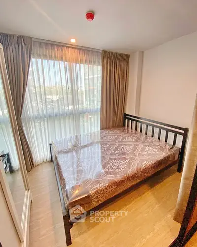 Cozy bedroom with large window and elegant curtains, featuring a stylish bed and wooden flooring.