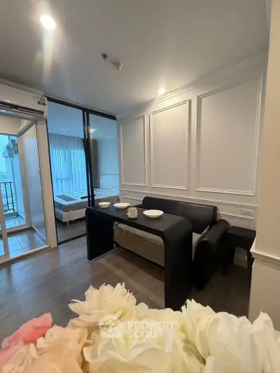 Modern living room with elegant decor and view into a cozy bedroom, featuring stylish furniture and ambient lighting.