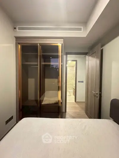 Modern bedroom with built-in wardrobe and ensuite bathroom in stylish apartment.